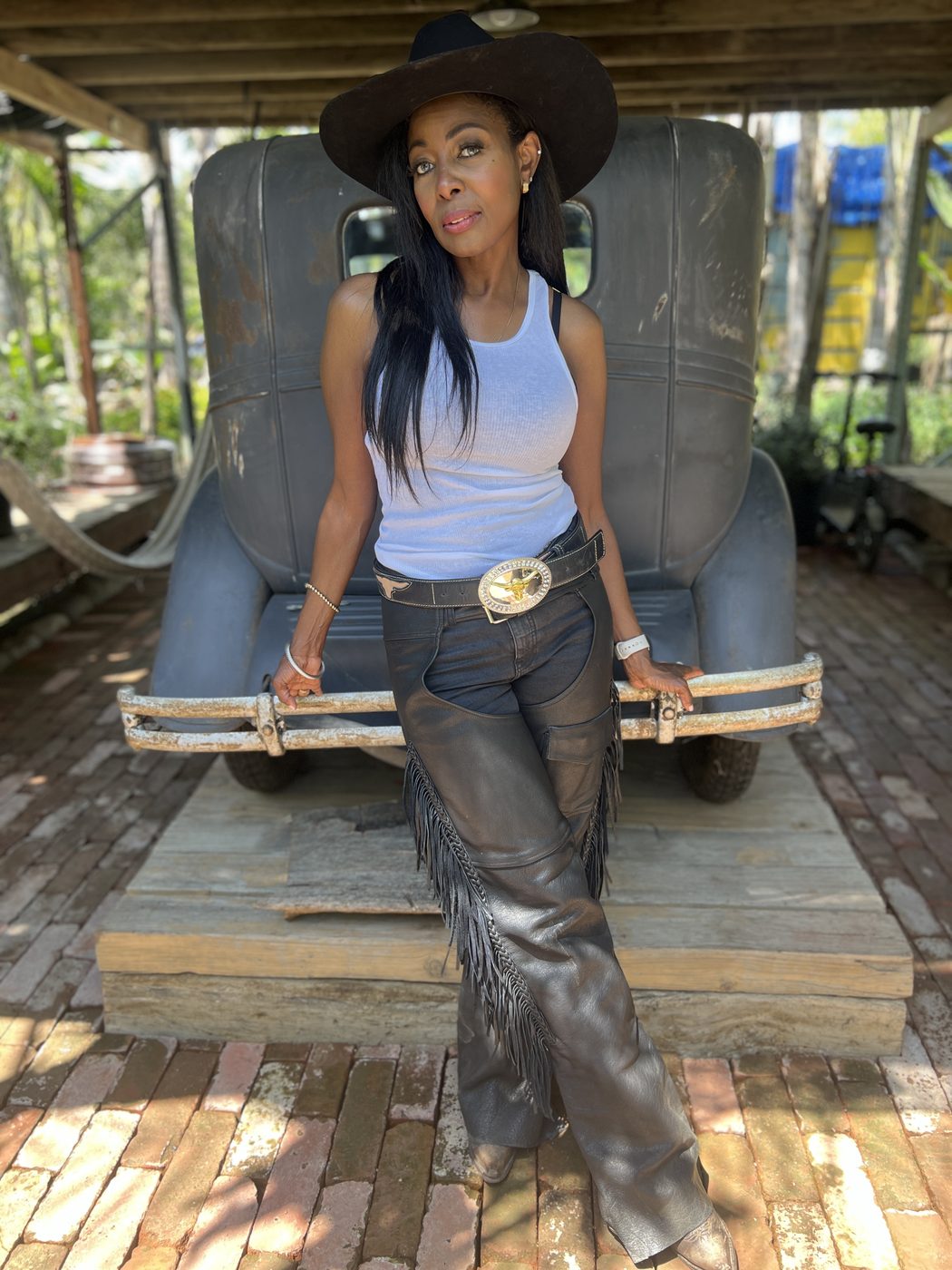 Brei Carter in white top and leather chaps by a vintage truck